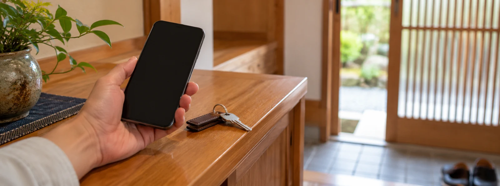 玄関の棚で住まいの相談用に携帯電話を手にする様子